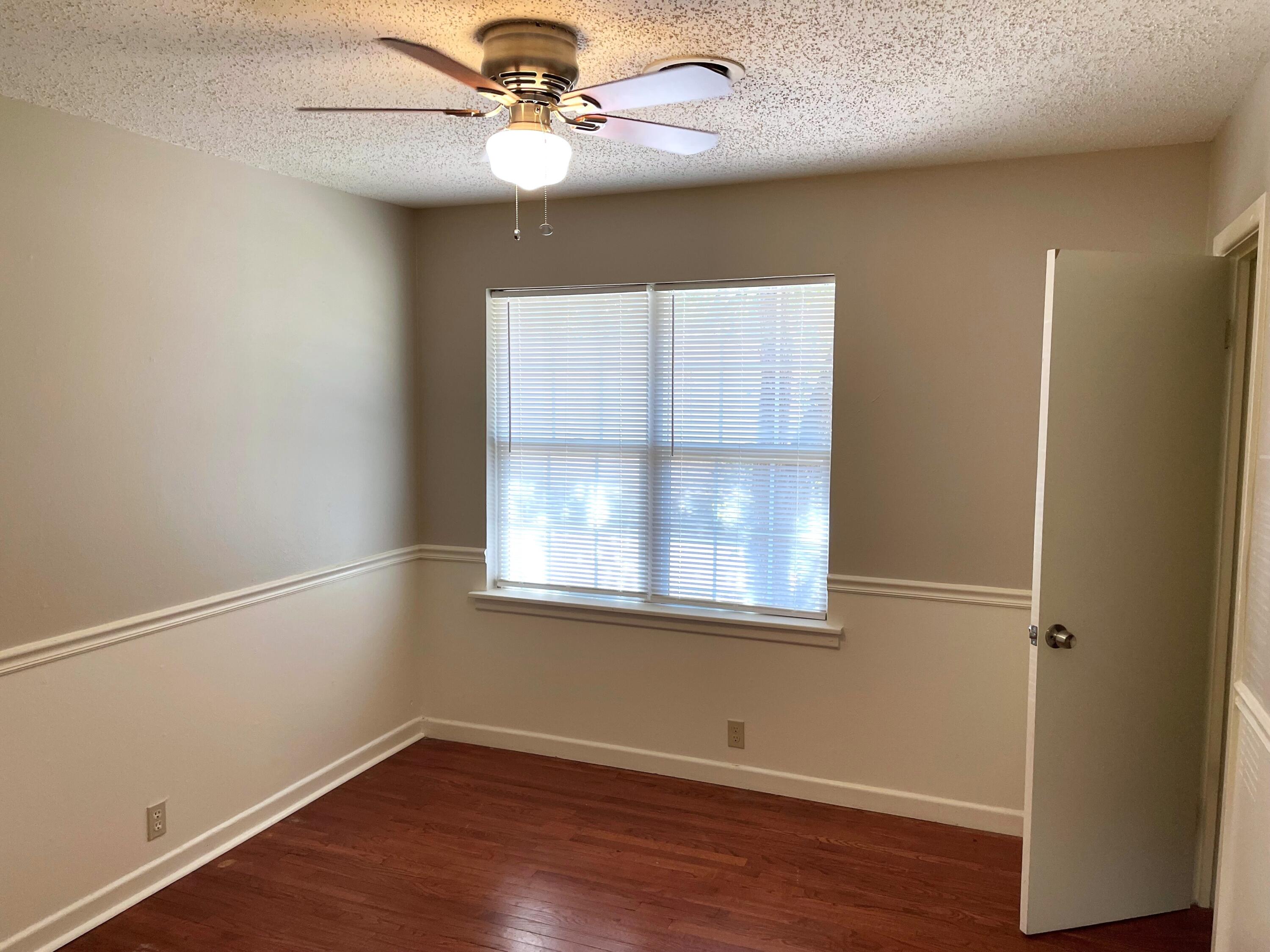 2409 Utica Avenue Lubbock, TX 79407 - Photo 15 of 22 an empty room with wooden floor chandelier fan and windows