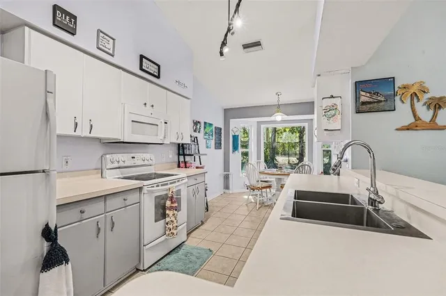 a large white kitchen with stainless steel appliances granite countertop a stove a sink dishwasher and white cabinets with wooden floor