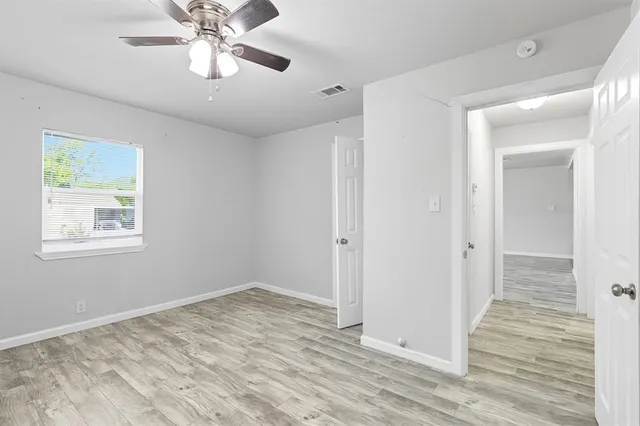 an empty room with a window and a fan