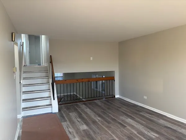 a view of a hallway with wooden floor and stairs