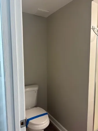 a white toilet sitting next to a small window