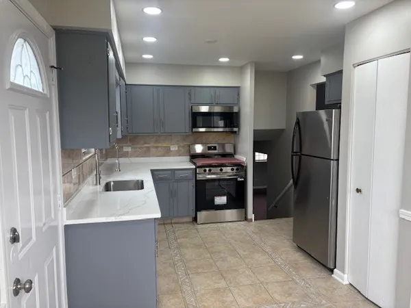 a kitchen with stainless steel appliances granite countertop a refrigerator a stove and a sink