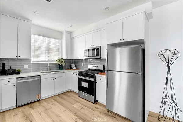 a kitchen with a refrigerator a stove a sink and white cabinets