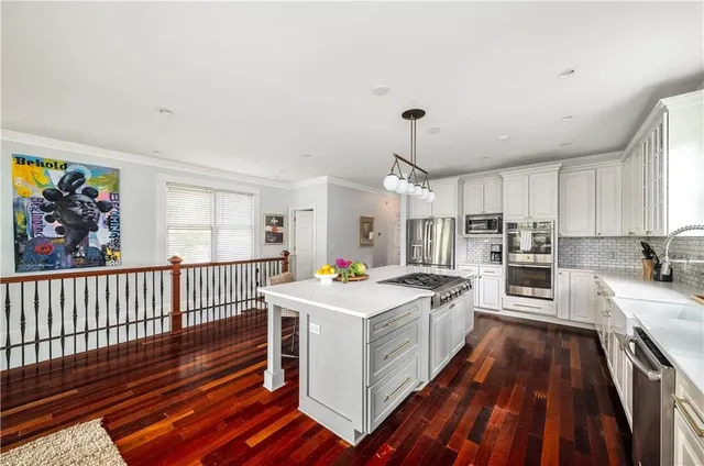 a open kitchen with stainless steel appliances a stove top oven a sink dishwasher and a dining table with wooden floor