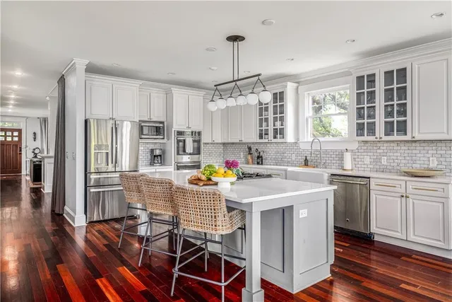 a kitchen with stainless steel appliances granite countertop a refrigerator a stove a sink dishwasher and white cabinets with wooden floor