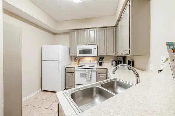 a kitchen with a refrigerator sink and white cabinets