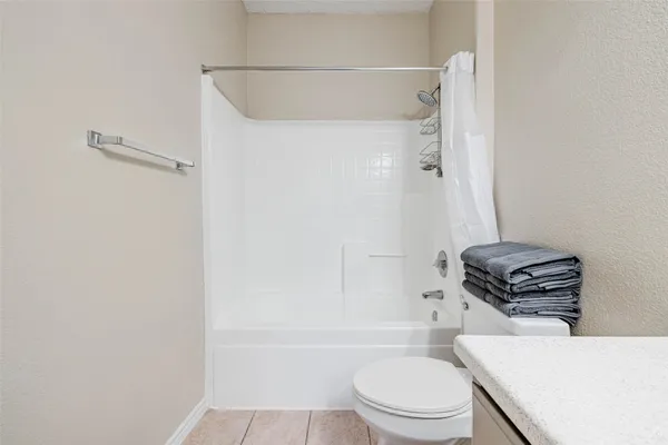 a bathroom with a granite countertop bathtub sink vanity mirror and toilet
