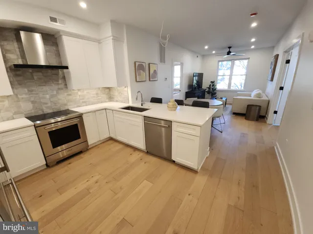 a kitchen with a sink dishwasher stove and white cabinets
