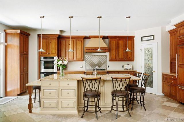 a kitchen with stainless steel appliances granite countertop a stove top oven a sink a dining table and chairs with wooden floor