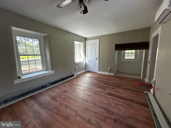 a view of an empty room with window and wooden floor
