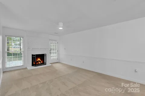 a view of an empty room with a fireplace and window