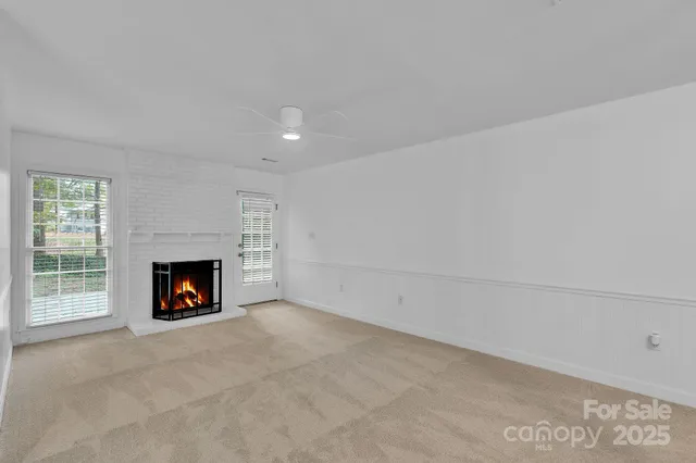 a view of an empty room with a fireplace and window