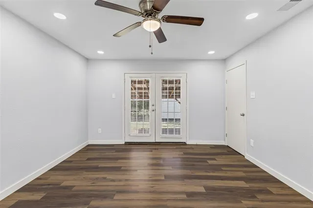 an empty room with wooden floor chandelier fan and windows