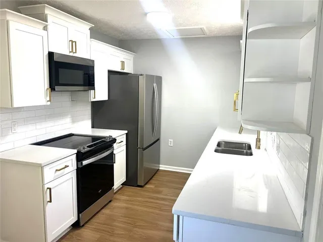 a kitchen with granite countertop a refrigerator stove and sink
