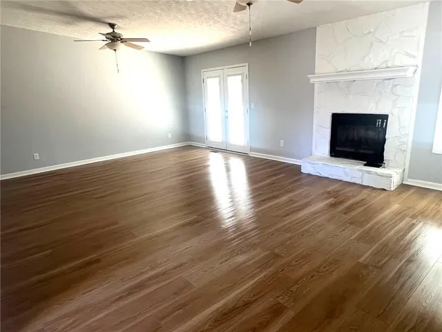 an empty room with windows fireplace and wooden floor