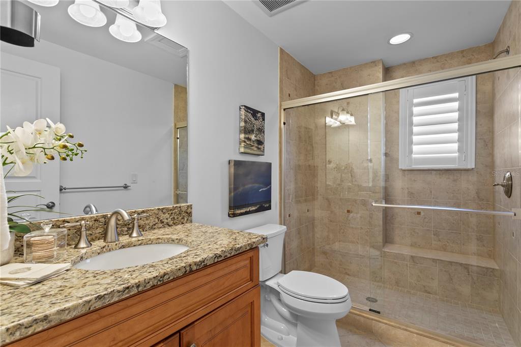 19730 Gulf Boulevard, Unit 400 Indian Rocks Beach, FL 33785 - Photo 55 of 90 a bathroom with a granite countertop sink a toilet a mirror and shower