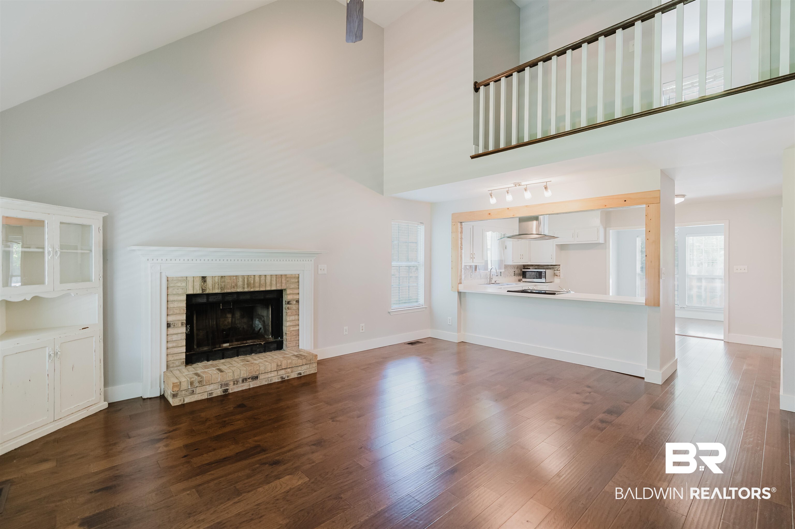 20460 Bishop Road Fairhope, AL 36532 - Photo 12 of 41 Unfurnished living room with dark wood-type flooring, high vaulted ceiling, a fireplace, and baseboards