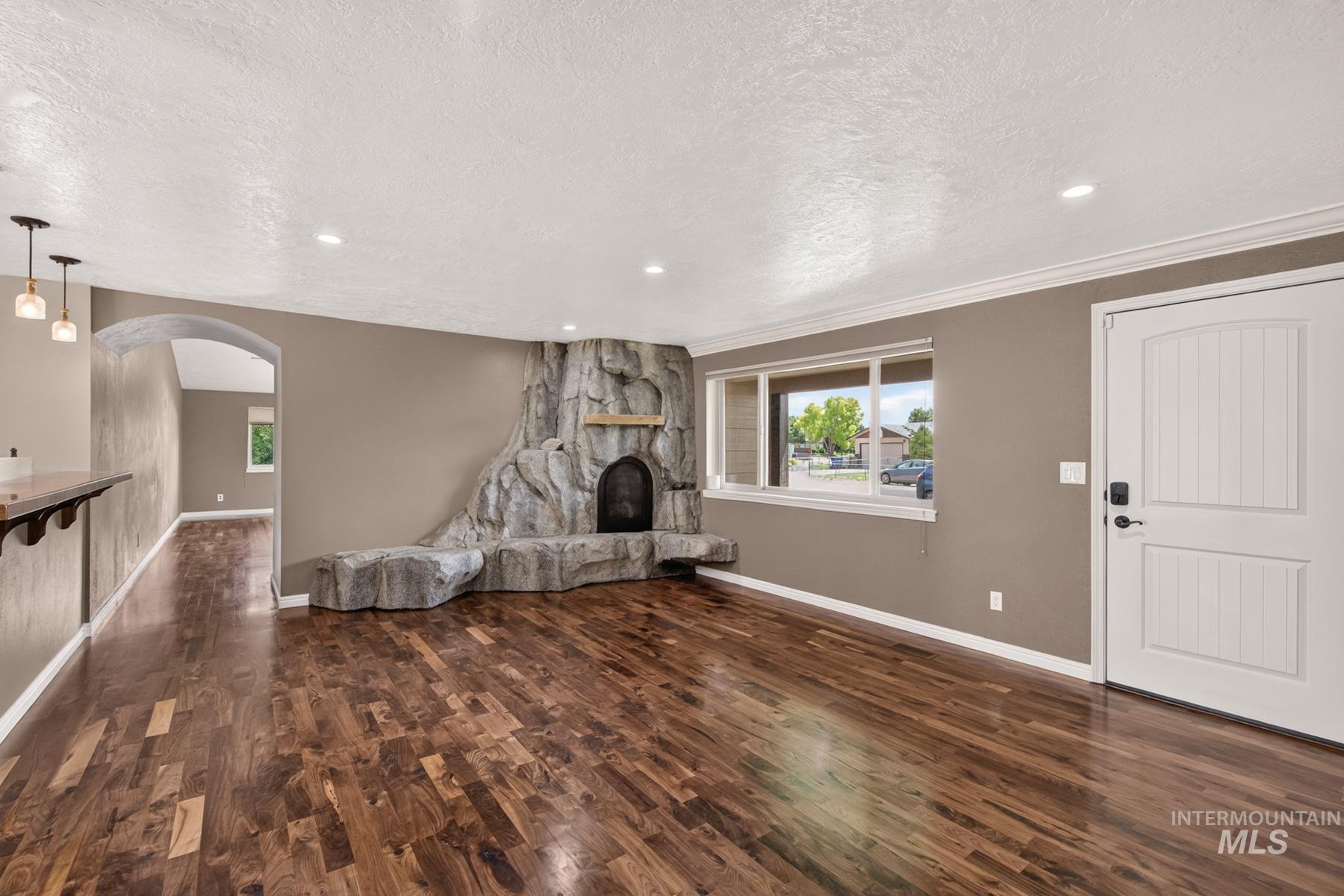 9622 Delaware Street Boise, ID 83709 - Photo 11 of 48 Spacious living area featuring rich wood-finish flooring, a stone-clad fireplace with mantel, recessed lighting, and crown molding