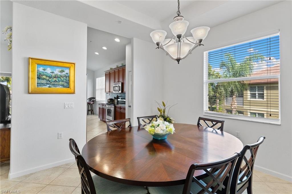6693 Alden Woods Circle, Unit 202 Naples, FL 34113 - Photo 12 of 25 a view of a dining room with furniture a chandelier and wooden floor