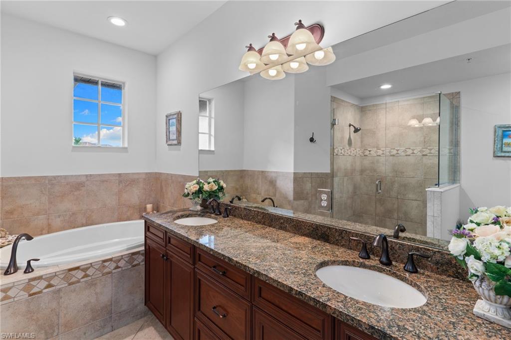 6693 Alden Woods Circle, Unit 202 Naples, FL 34113 - Photo 21 of 25 a bathroom with a granite countertop bathtub sink and mirror