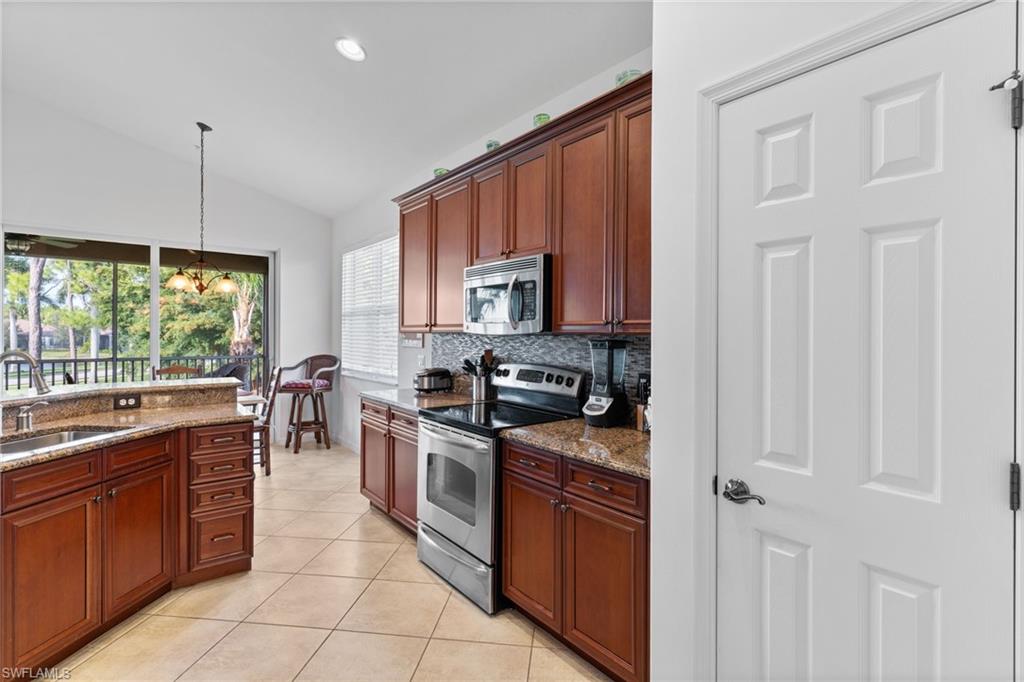 6693 Alden Woods Circle, Unit 202 Naples, FL 34113 - Photo 3 of 25 a kitchen with stainless steel appliances granite countertop a stove top oven a sink dishwasher a dining table and chairs with wooden floor