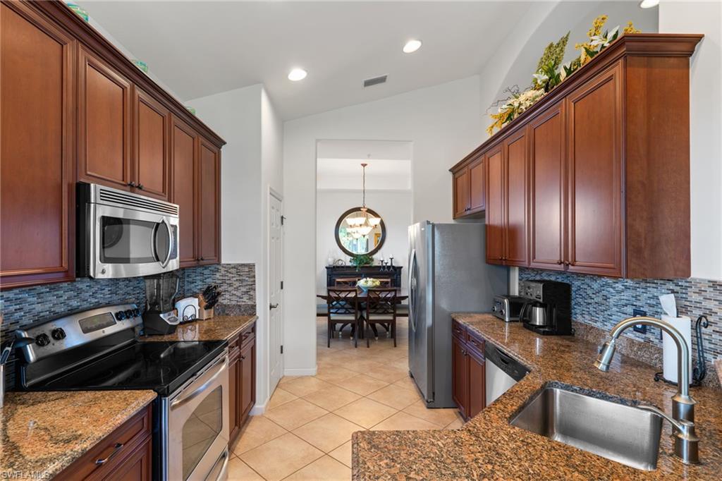 6693 Alden Woods Circle, Unit 202 Naples, FL 34113 - Photo 6 of 25 a kitchen with granite countertop a stove a sink and a microwave