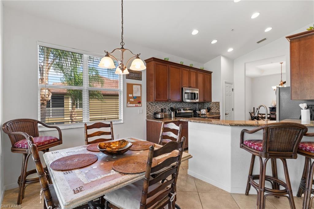 6693 Alden Woods Circle, Unit 202 Naples, FL 34113 - Photo 7 of 25 a kitchen with stainless steel appliances granite countertop a stove a sink dishwasher a dining table and chairs with wooden floor