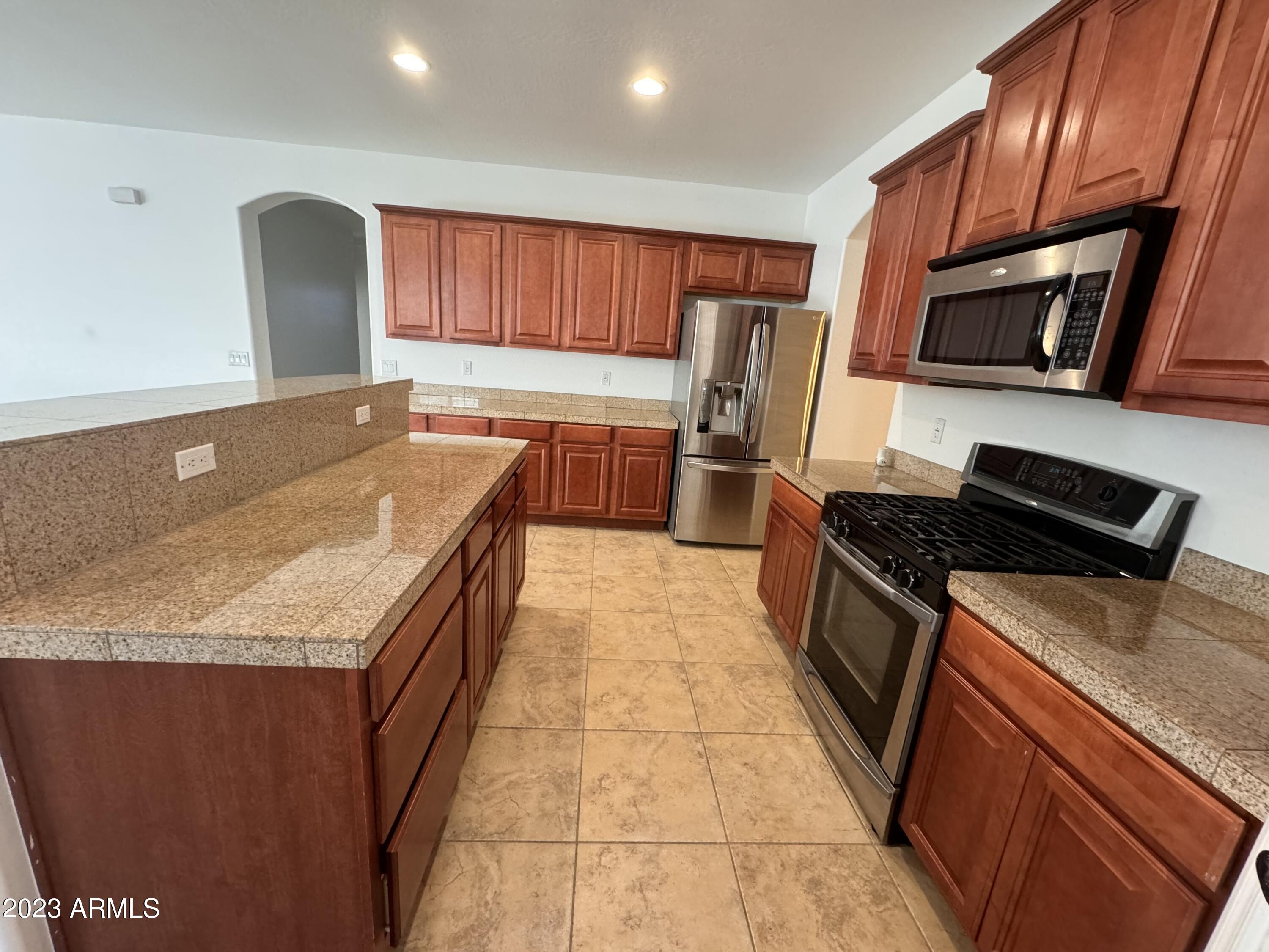 3753 East Phelps Street Gilbert, AZ 85295 - Photo 9 of 18 a kitchen with stainless steel appliances granite countertop a stove a sink and a microwave