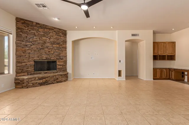 an empty room with windows and fireplace