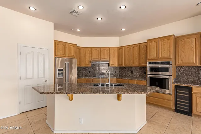 a kitchen with kitchen island granite countertop a stove a sink and a refrigerator