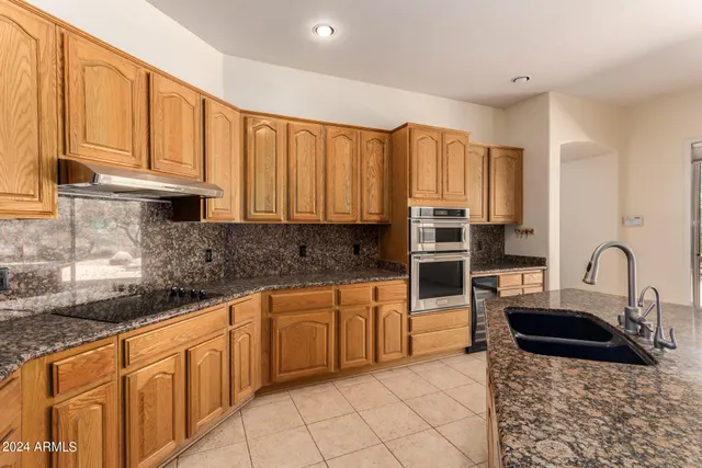 a kitchen with stainless steel appliances granite countertop a stove a sink and a microwave
