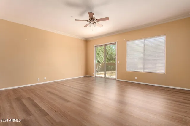 an empty room with wooden floor fan and windows