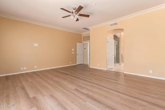 an empty room with wooden floor and a ceiling fan