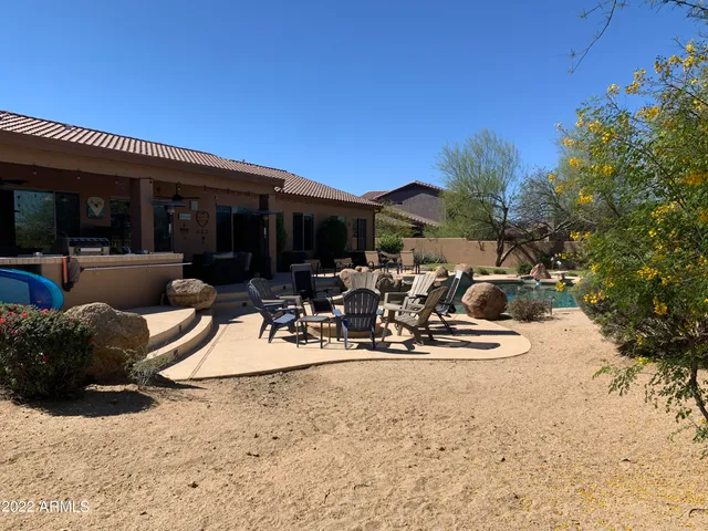 a view of a patio with table and chairs potted plants and a large tree