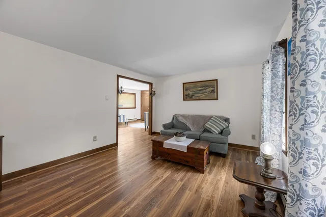 a living room with furniture a fireplace and a dining table with wooden floor