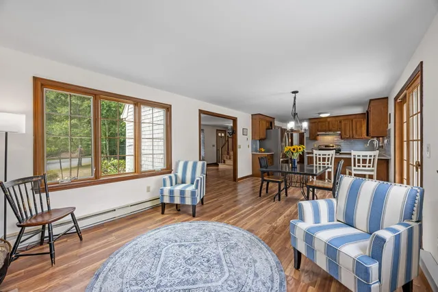 a kitchen with stainless steel appliances granite countertop a stove top oven a sink a dining table and chairs with wooden floor