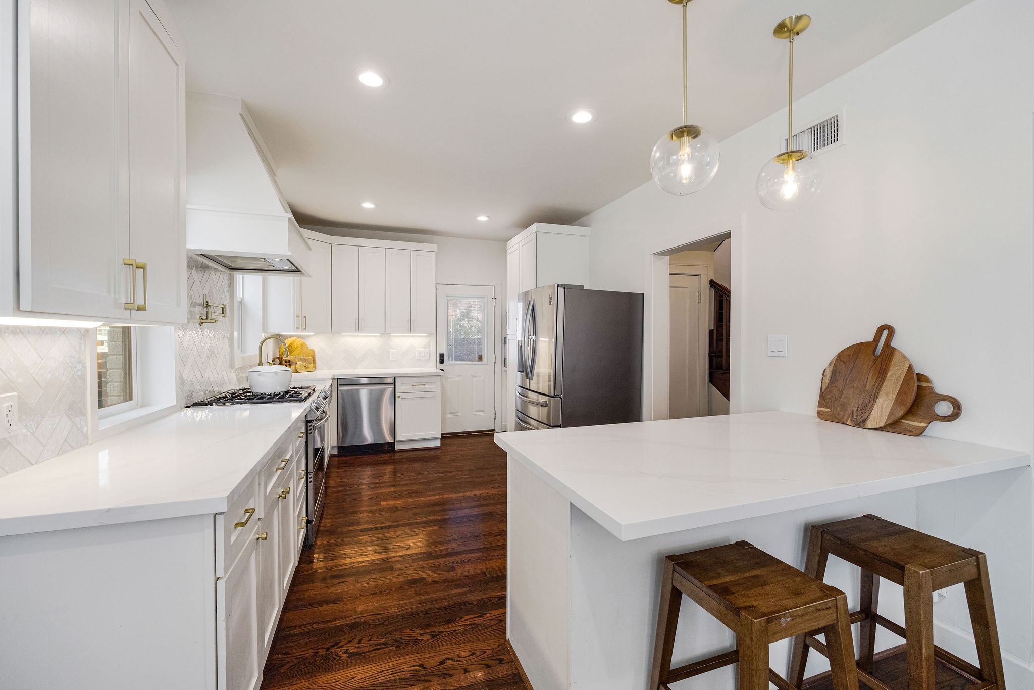 2613 Wichita Street Houston, TX 77004 - Photo 8 of 25 Updated kitchen featuring quartz countertops, stainless steel appliances, custom cabinetry, and a peninsula with bar seating.