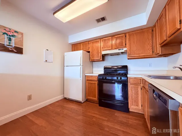 a kitchen with stainless steel appliances granite countertop a refrigerator a stove and a sink