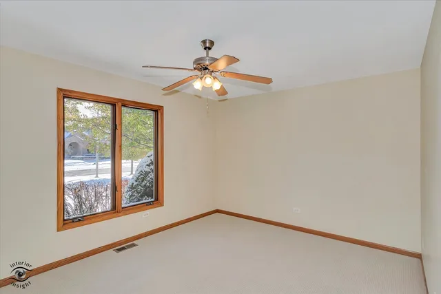 a view of an empty room with chandelier fan and a window