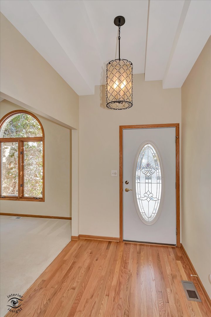 19612 Waterford Lane Mokena, IL 60448 - Photo 3 of 28 an empty room with wooden floor a chandelier and a window