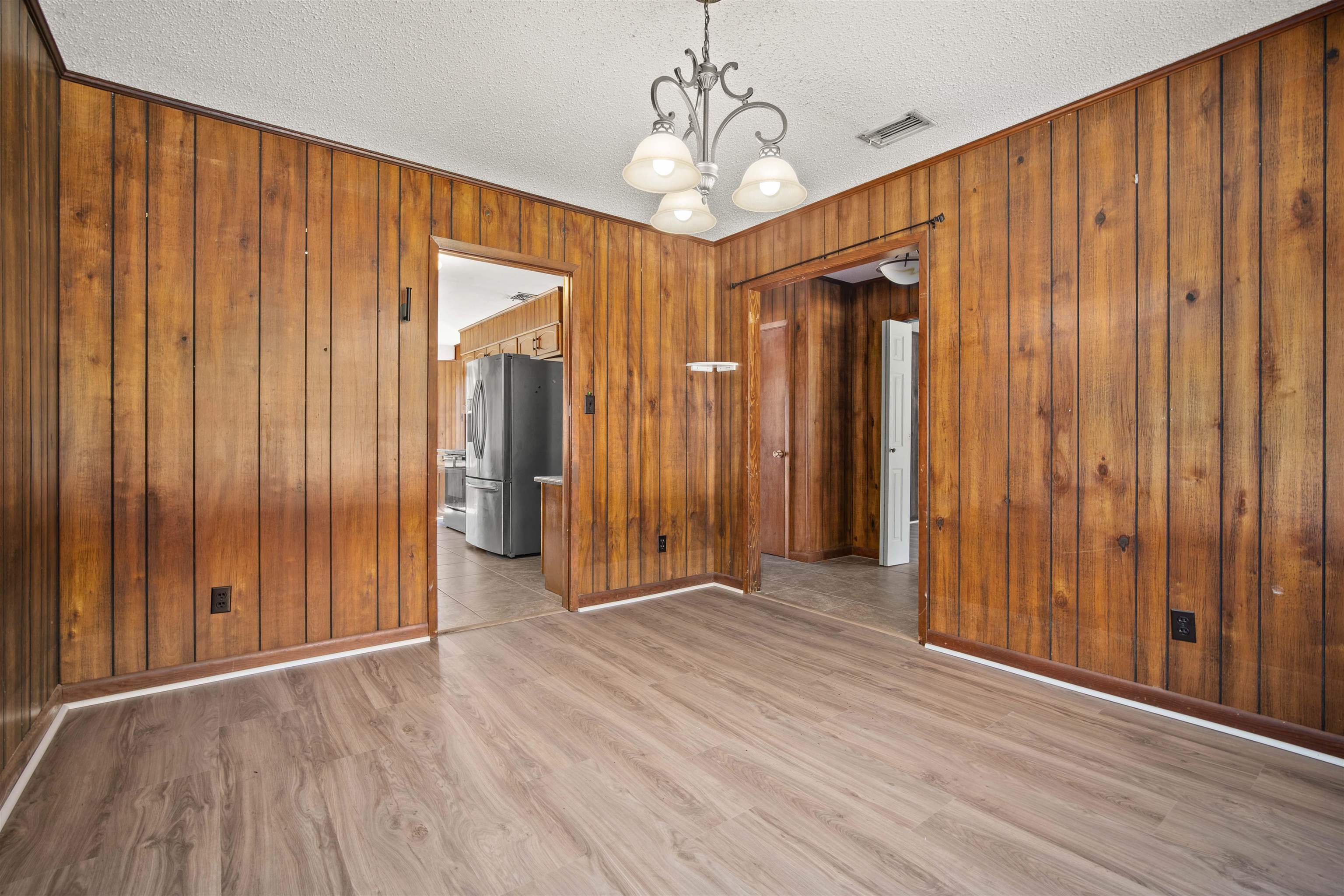10285 Argyle Road Irvington, AL 36544 - Photo 15 of 28 Spare room with a chandelier, light wood finished floors, wooden walls, and a textured ceiling