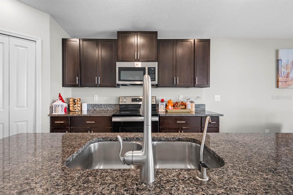 889 Calico Scallop Street Ruskin, FL 33570 - Photo 11 of 37 a kitchen with a sink cabinets and stainless steel appliances