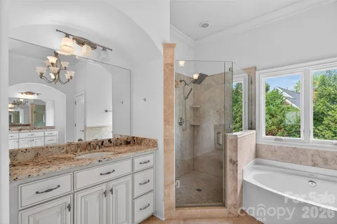 a bathroom with a granite countertop tub sink and mirror