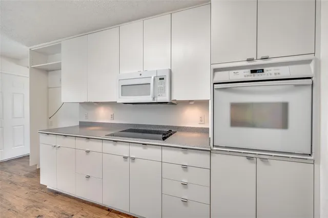 a kitchen with granite countertop white cabinets and white appliances