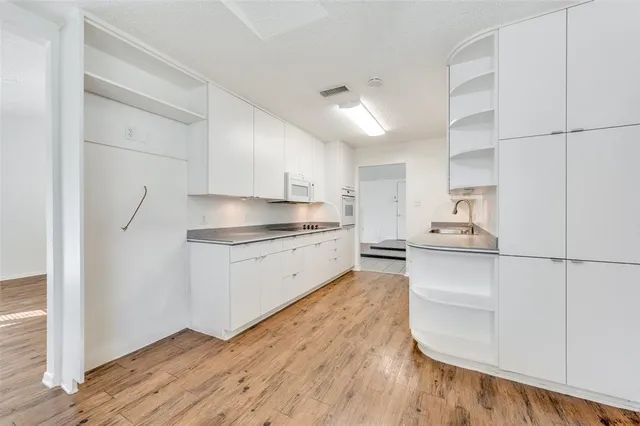 a kitchen with granite countertop white cabinets and wooden floor