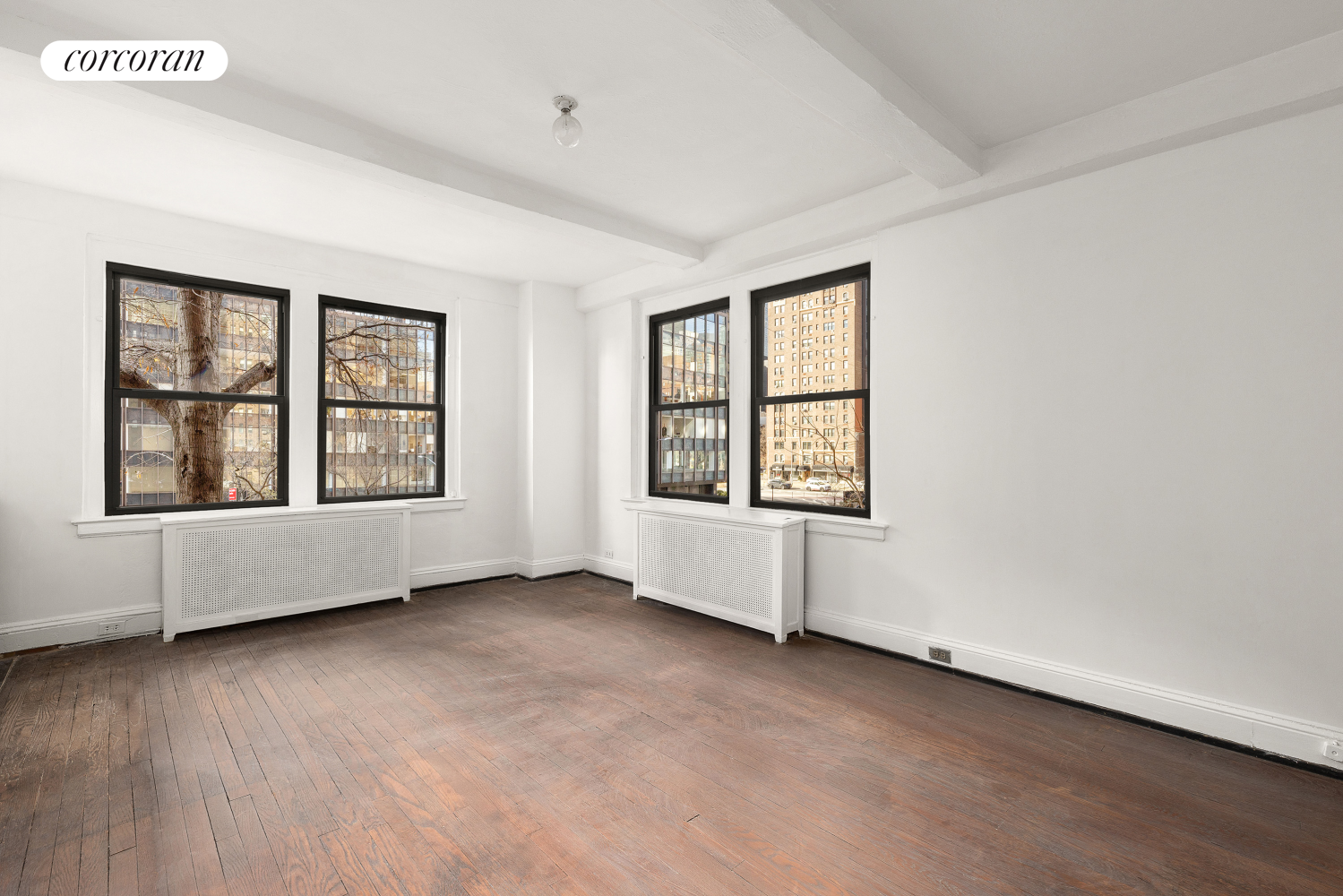 an empty room with wooden floor and windows