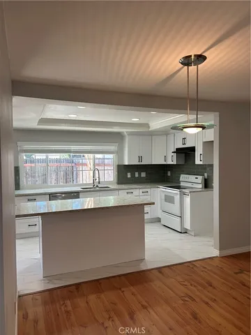 a kitchen with granite countertop white cabinets and white appliances
