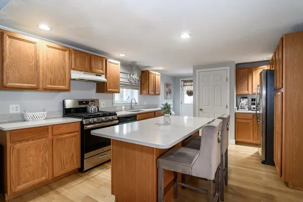 a kitchen with stainless steel appliances granite countertop a table chairs sink refrigerator and cabinets