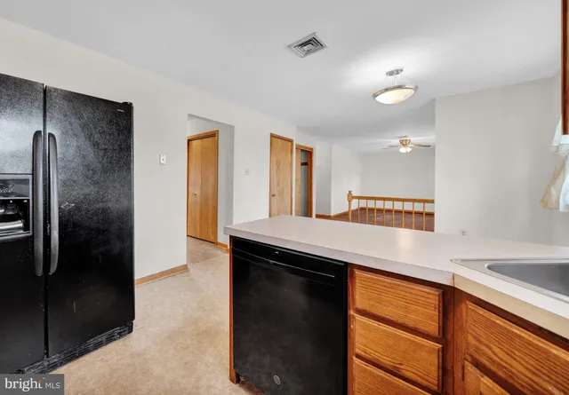 an empty room with chandelier fan and windows