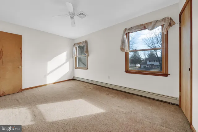 an empty room with ceiling fan and windows